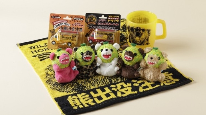 北海道限定の「熊出没注意」グッズと、メロンの着ぐるみを着たクマのぬいぐるみ