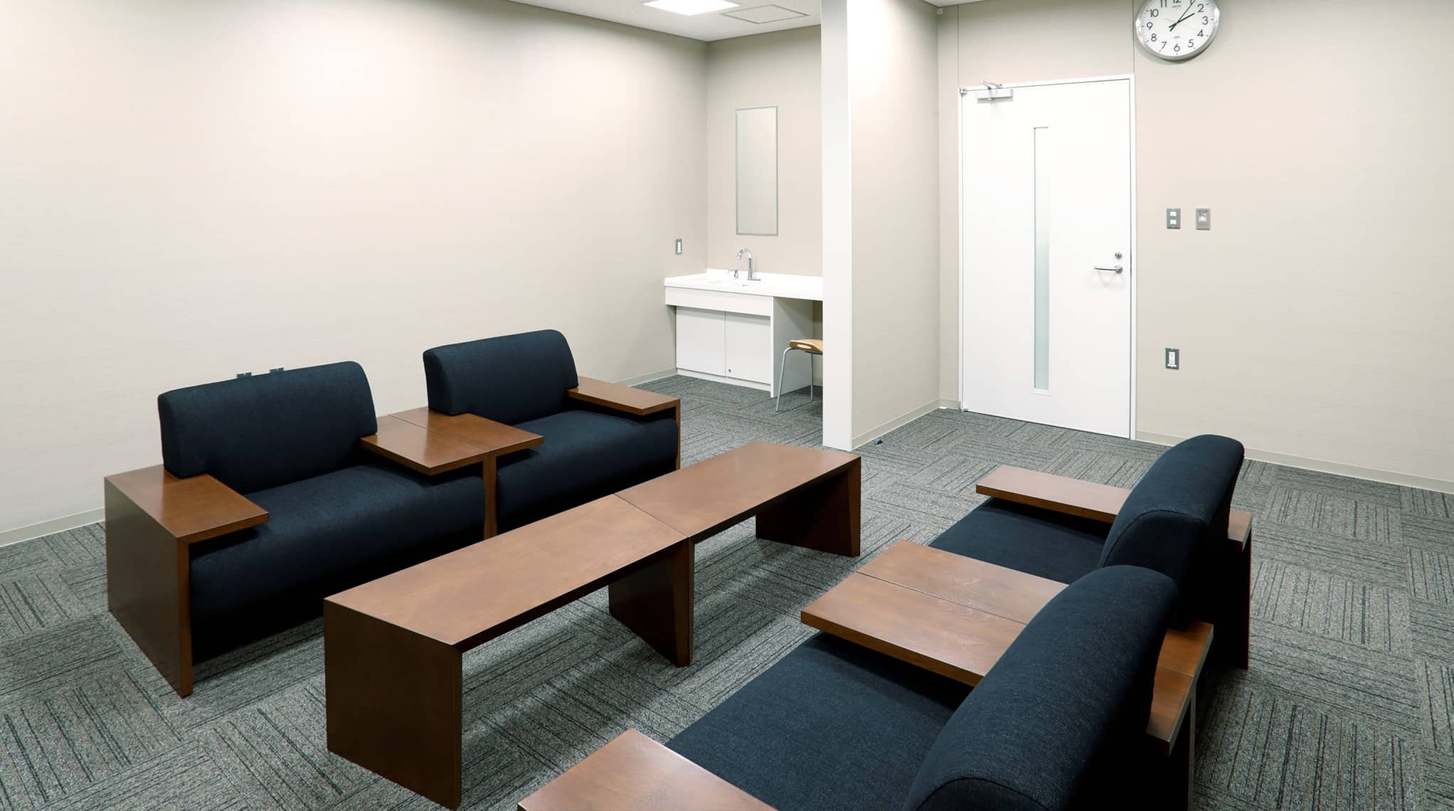 特別控室。壁側に洗面台が設置され、中央にテーブルとテーブルを囲んで向かい合うソファーが置かれている様子