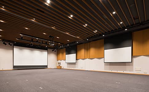メメインホールに電動昇降式スクリーンが3台設置され、LED照明が多数備えられている様子