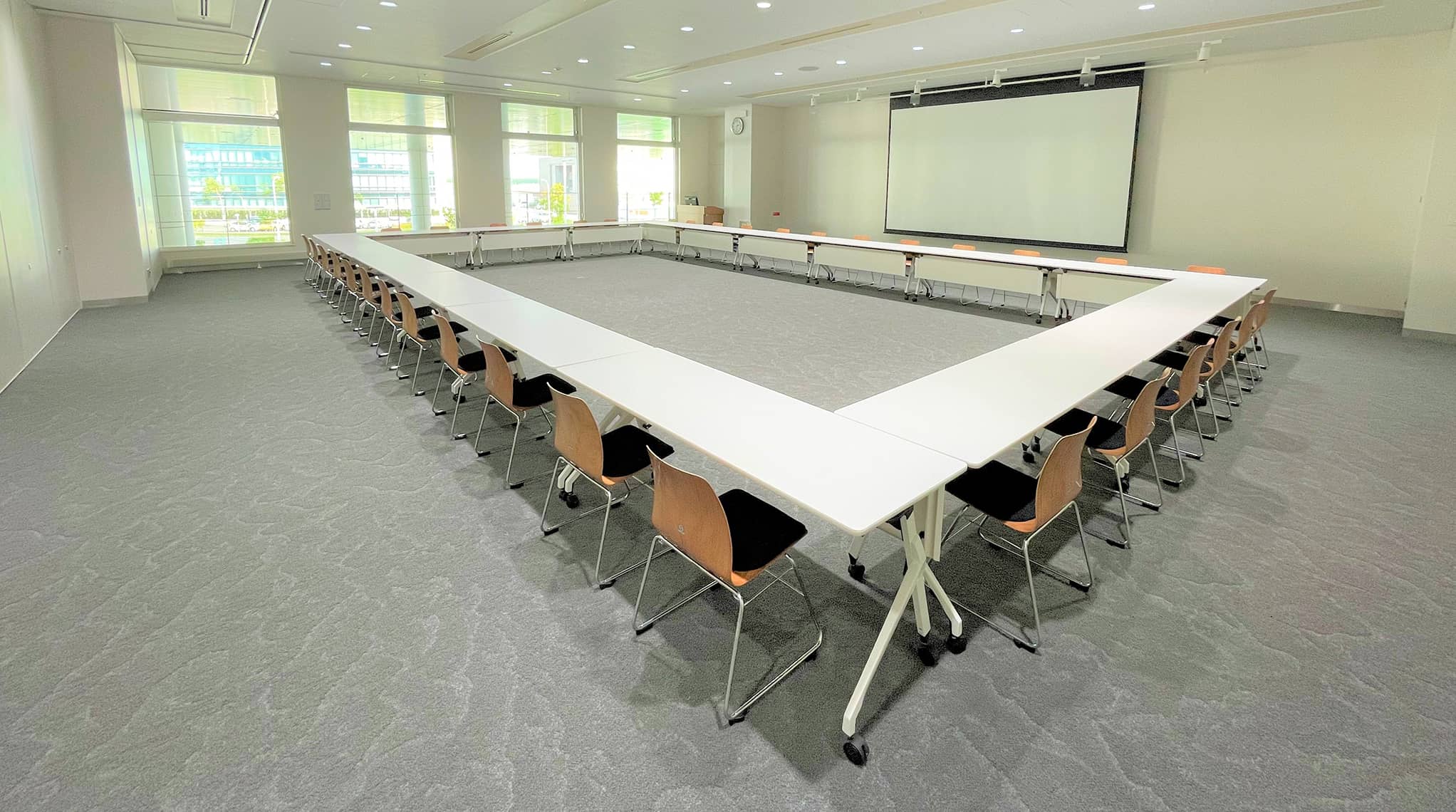 半面使用のコの字形式レイアウトで、座席・スクリーン・窓側まで全体が見渡せる様子