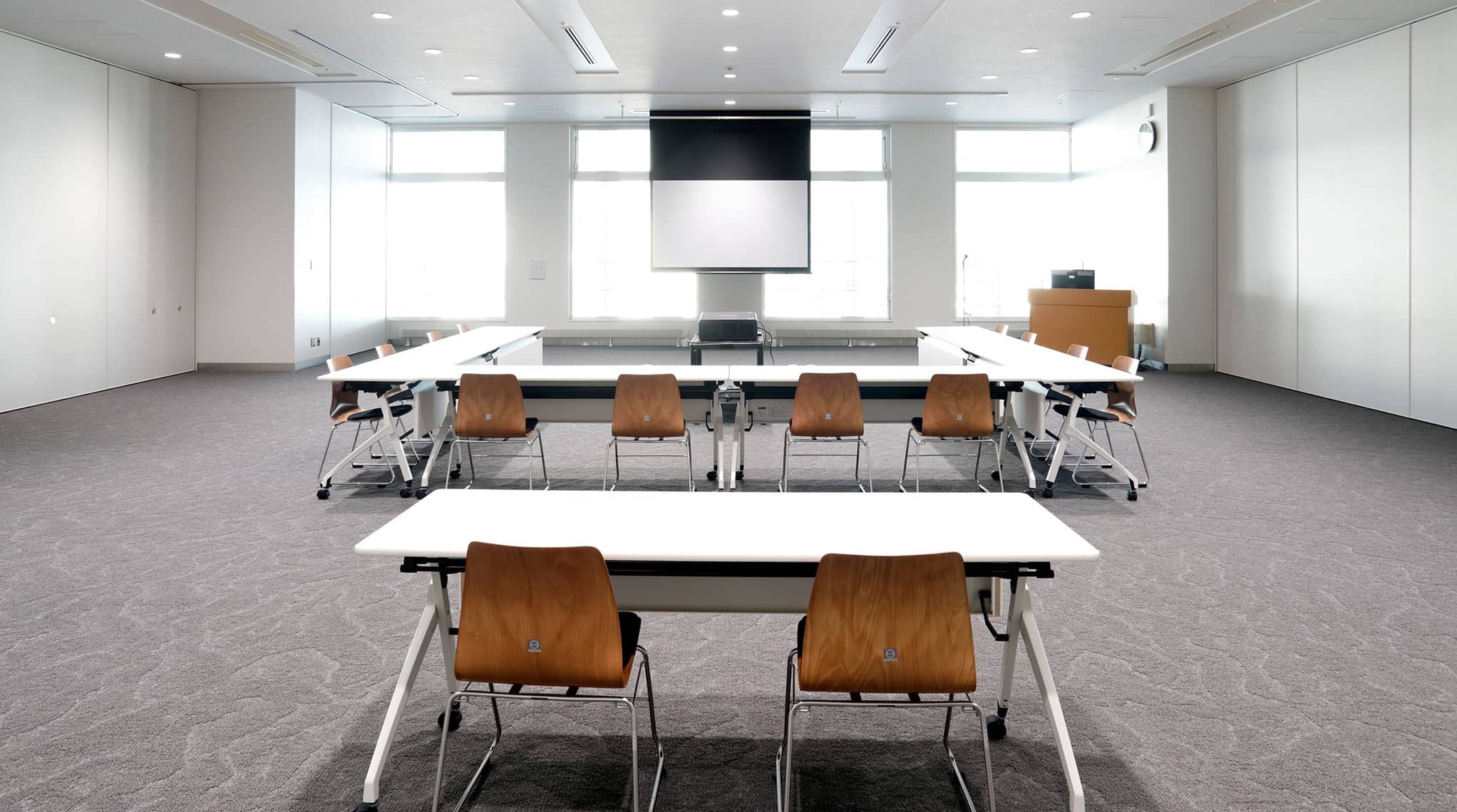 半面使用時のコの字形式レイアウトで、後方席からプロジェクターとスクリーンを見た様子